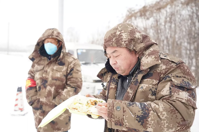 鳳城負責防疫的工作人員在風雪中吃飯。