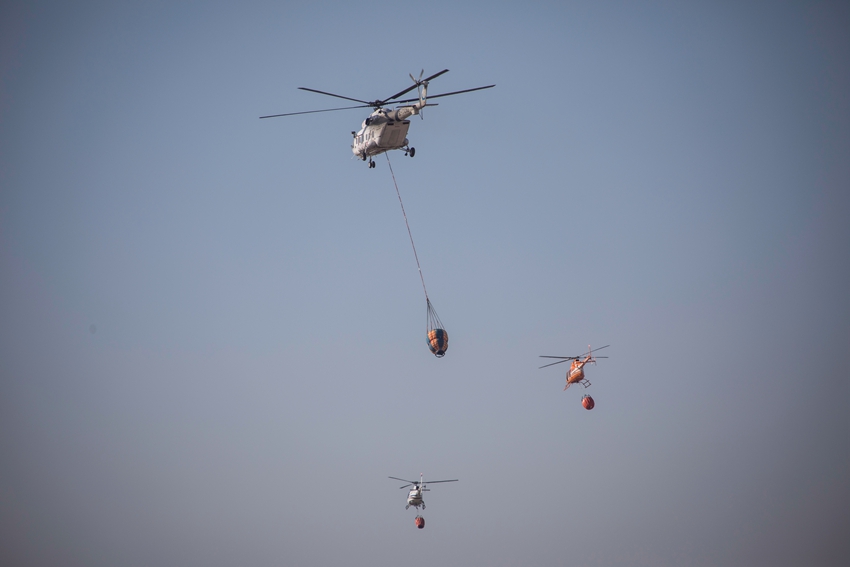 三架直升飛機飛向附近水源，為吊桶裝水。