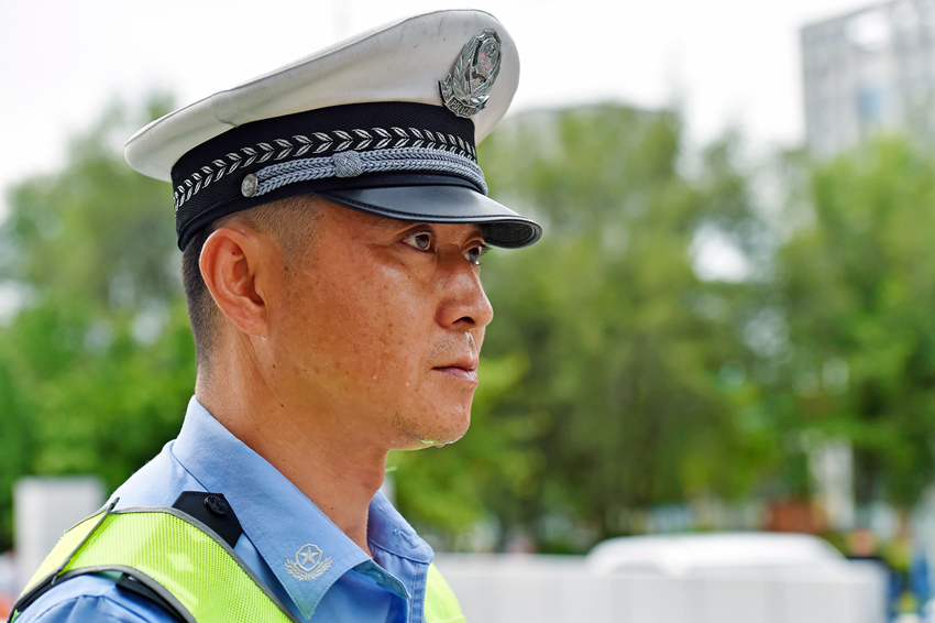 本溪一名交警正在烈日下疏導交通，汗水滴落臉頰。（遼寧省公安廳供圖）