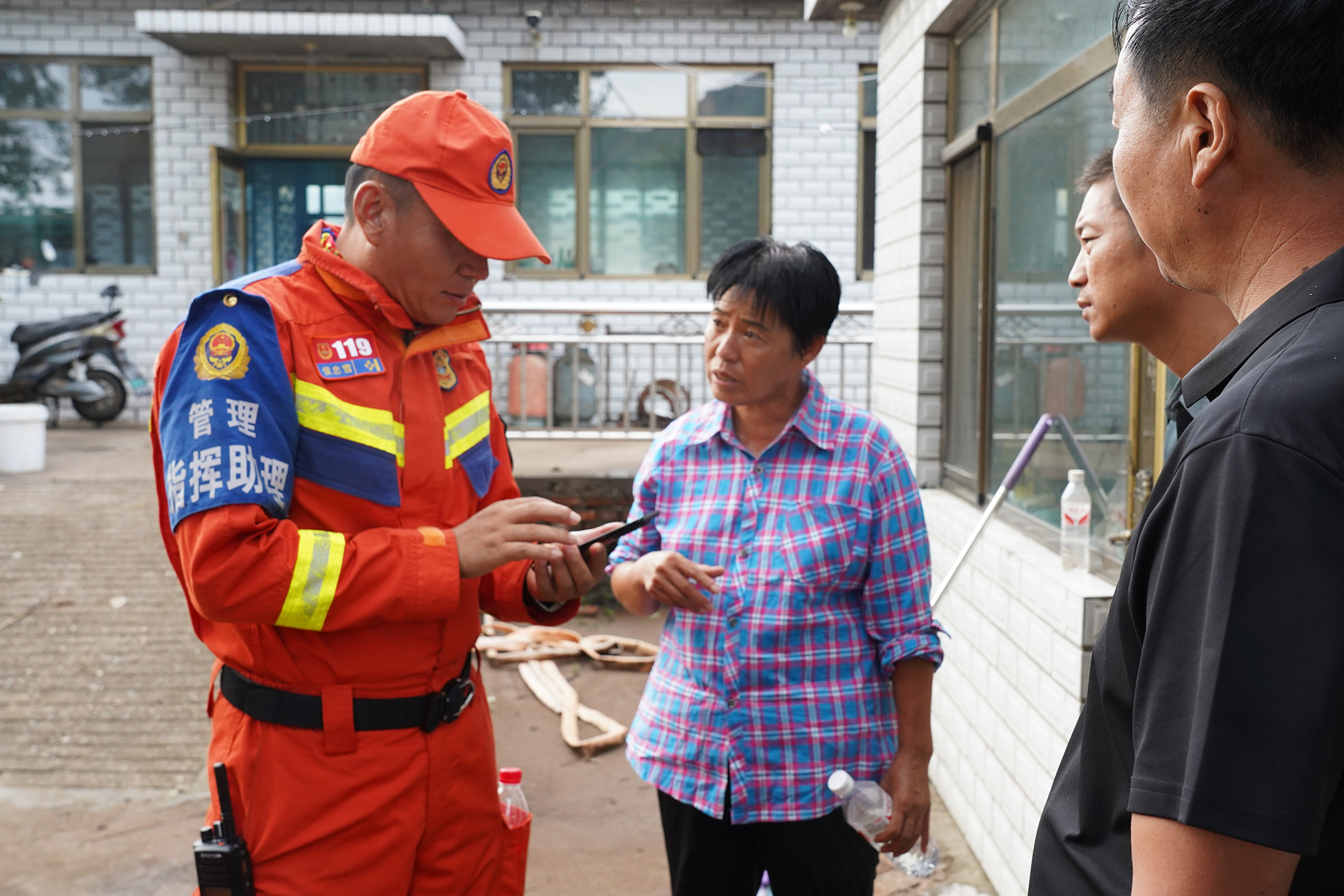 8月22日，辽宁省葫芦岛市建昌县黑山科乡杨树底下村，消防员正在向村民询问村内需要转移的人员情况。辽宁省消防救援总队供图