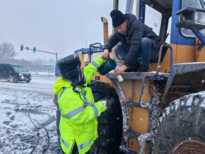 公安交警为除雪车司机递上热水。人民网记者 王斯文摄