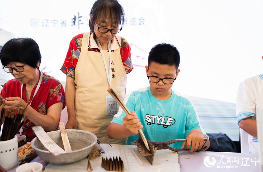 2025辽宁省非遗夏季博览会现场，小朋友尝试制笔技艺。人民网记者 邱宇哲摄
