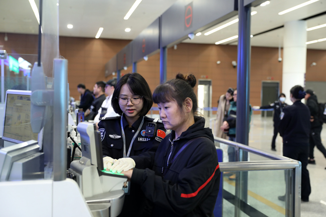 辽宁沈阳边检站移民管理警察帮助旅客录入指纹。