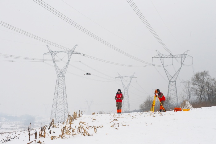 国网本溪供电公司输电运维人员用全站仪观察500千伏白徐线雪后运行状态。 姜云峰 摄