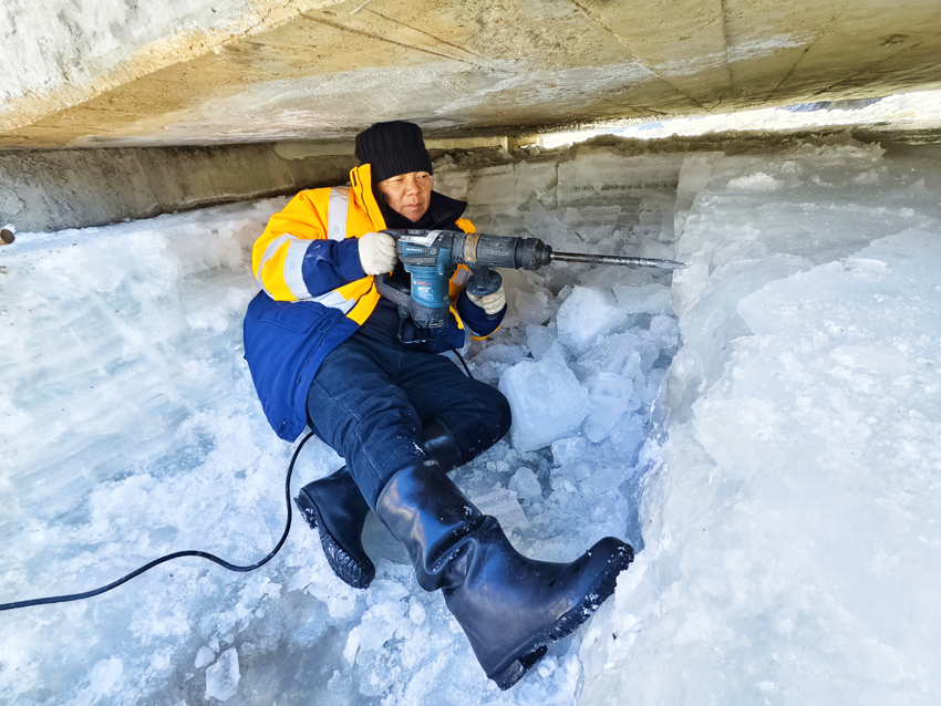 作业人员半躺在冰面上，使用电镐进行破冰。迟金海摄。