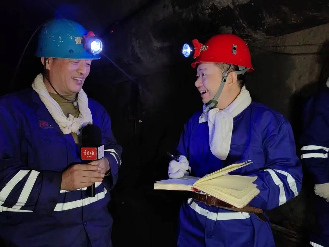 記者張小龍（右）在井下680米深處採訪老虎台礦掘修區礦工郝立鋼。 曹起龍 攝