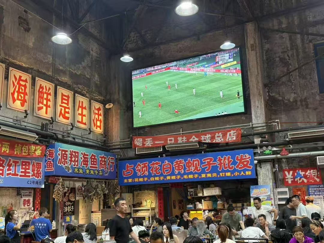 “东北超”大连第二现场，市民边品海鲜边看球赛。曲琦摄