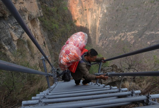 5月13日，四川省昭覺縣阿土列爾村村民某色達體沿著鋼梯下山，告別連續5代人居住的“懸崖村”，開始新生活。新華社記者 江宏景 攝