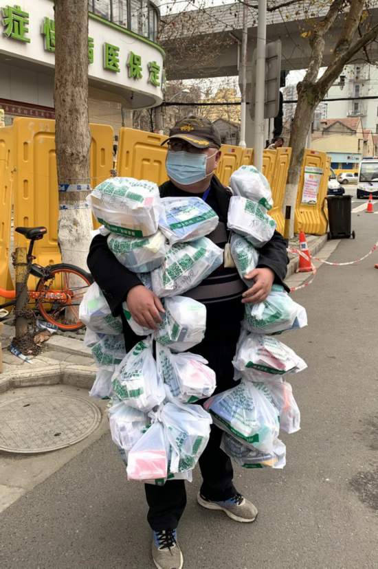 2月24日，在武漢市江岸區黃石路漢口大藥房，惠民苑社區網格員豐楓把為居民購買的藥挂在身上。新華社發